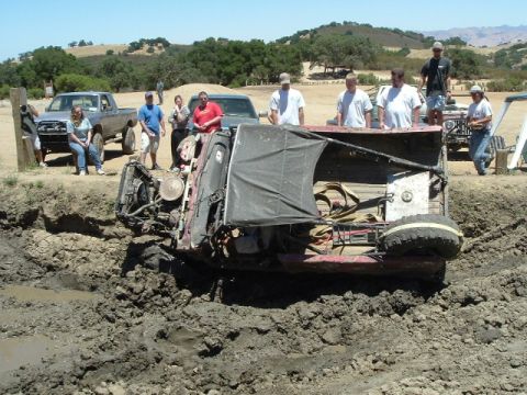 1989 Ford Bronco - A group of people watch as an off-road vehicle is stuck in a mud pit.