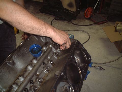 1967 Ford Galaxie - A mechanic works on an engine block, which is part of a vehicle's internal mechanics.