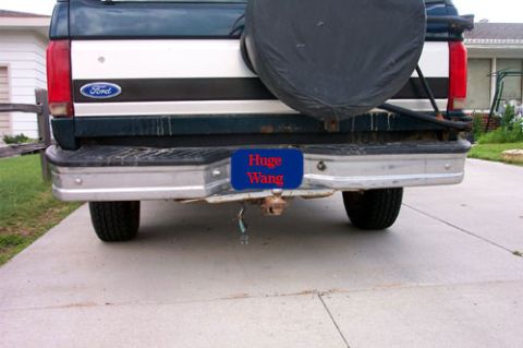 1995 Ford Bronco - Rear view of a dark green and white two-tone 1990s Ford full-size SUV on a concrete driveway, showing the blue Ford oval tailgate badge, a…