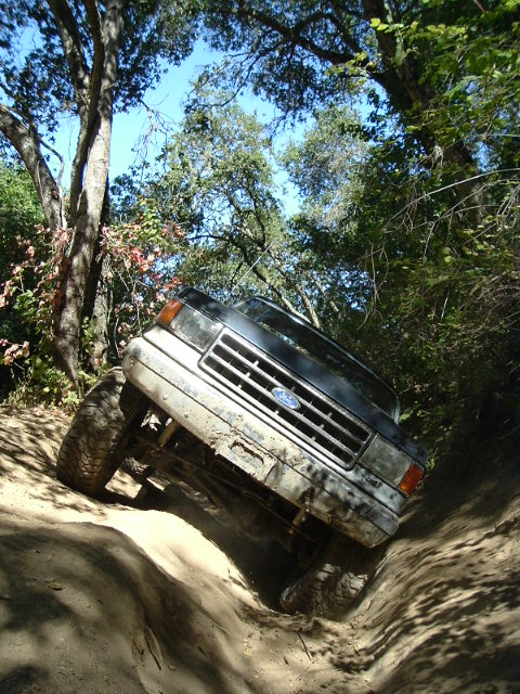 1989 Ford Bronco - Ford Bronco navigating a challenging off-road trail with steep inclines and turns.