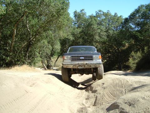 1989 Ford Bronco - This lifted Ford F-Series truck navigates a sandy, off-road path.