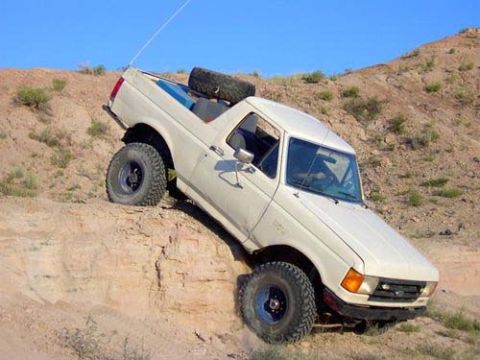 1987 Ford Bronco - This 1987 Ford Bronco is navigating a steep, rocky incline under a clear blue sky.