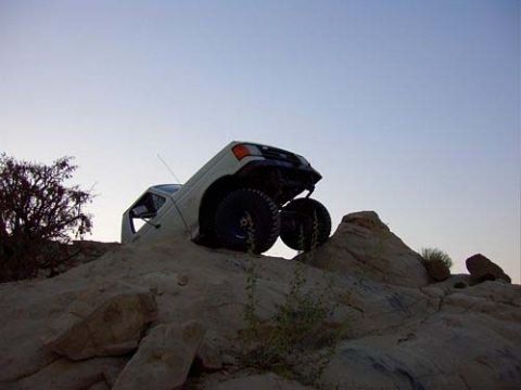 1987 Ford Bronco - Off-road Bronco navigating a steep, rocky incline under a clear sky.