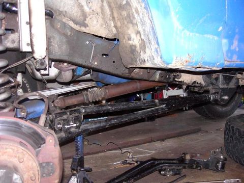 1980 Ford Bronco - Close-up view of the undercarriage of a blue vehicle, showing suspension and drivetrain parts.