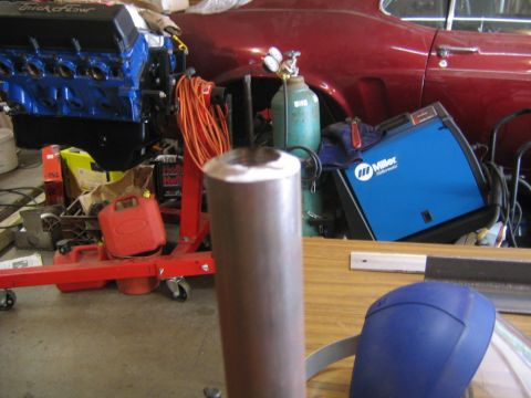 1978 Ford Bronco - A cluttered garage workshop with a blue Ford engine block on an engine stand, a blue Miller Millermatic welder, a green gas cylinder with r…