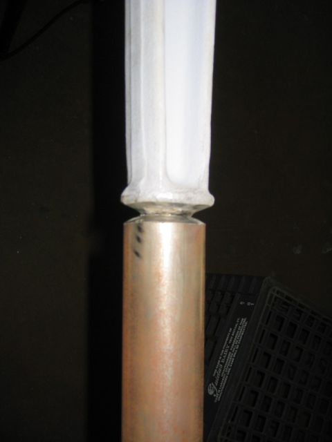1978 Ford Bronco - Close-up of a metal tubular part with a fresh weld joining a copper/bronze-toned lower tube to a white primer-coated upper section, resting…