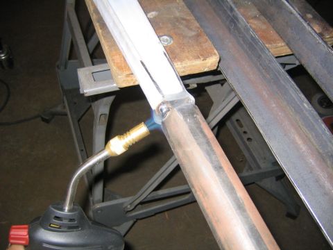 1978 Ford Bronco - A handheld propane/MAP gas torch heats a brazed or soldered joint between an aluminum bar and a copper-colored tube, likely fabricating sus…