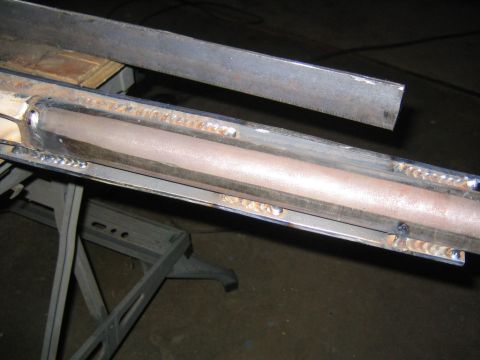 1978 Ford Bronco - Close-up of a fabricated steel suspension component with a copper-colored round tube welded between metal plates, showing fresh MIG/TIG wel…