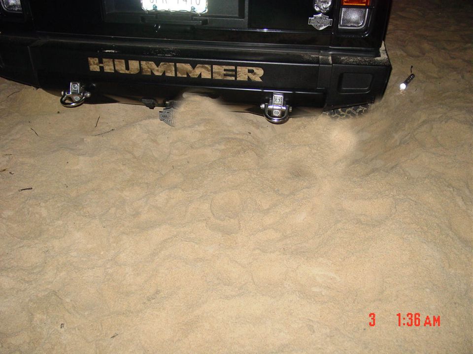 Black Hummer rear with HUMMER lettering and dual hitches, parked in sand at night