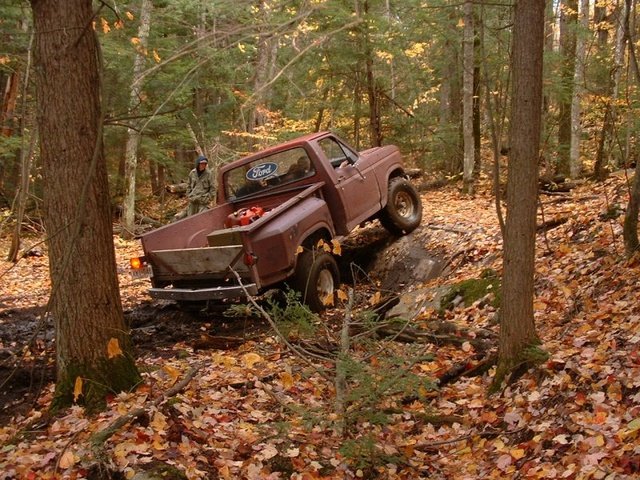Brown 1980 Ford F-100 navigating a muddy forest trail