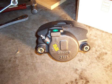 1994 Ford Bronco - A single brake caliper is shown on a concrete surface with tools in the background.