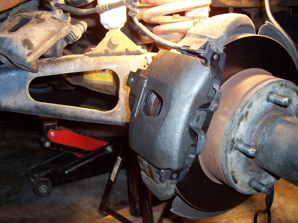 Brake caliper installed over rotor on truck front hub with wheel removed