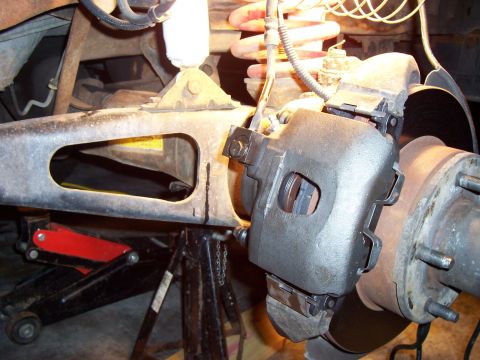 1994 Ford Bronco - This image shows a close-up view of a vehicle's brake caliper and suspension system, supported by a jack and stand.