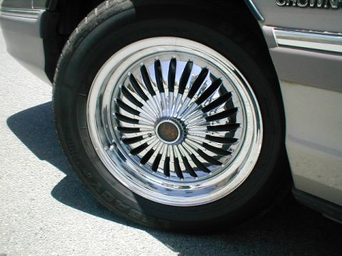1994 Ford Crown Victoria - A close-up view of a custom chrome wire wheel with black spokes on a vehicle.