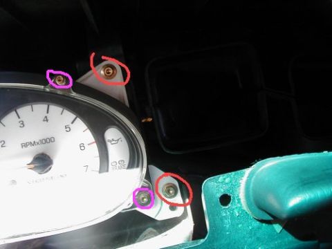 1997 Ford Taurus - Close-up of screws being removed from a vehicle's instrument cluster.