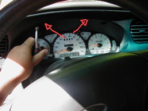 1997 Ford Taurus - Screwdriver is used to remove screws from the instrument cluster trim panel of a 1997 Ford Taurus.