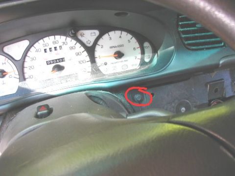 1997 Ford Taurus - Dashboard gauges and steering wheel area of a car, with a circled screw indicating a repair point.