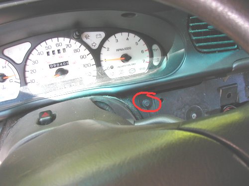Close-up of car dashboard gauges with odometer showing 090408. A screw is circled in red