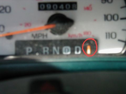 1997 Ford Taurus - The gear selector indicator light is illuminated orange in this close-up view of a vehicle's instrument cluster.