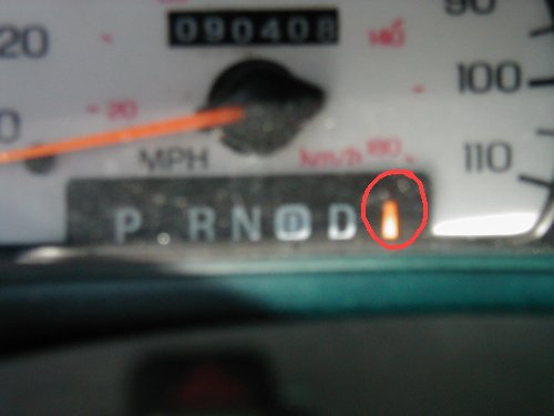 Close-up of a car's gear selector indicator light illuminated orange