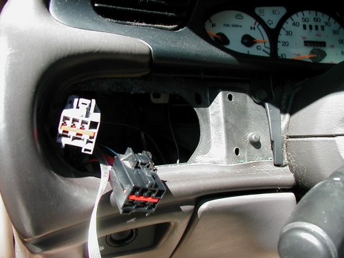car dashboard with radio and instrument cluster removed, showing wiring harnesses