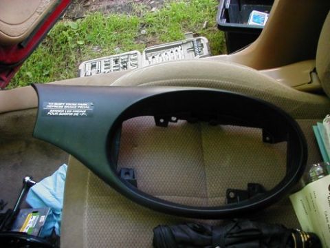 1997 Ford Taurus - A black plastic trim piece with bilingual instructions is shown removed from a car's interior.