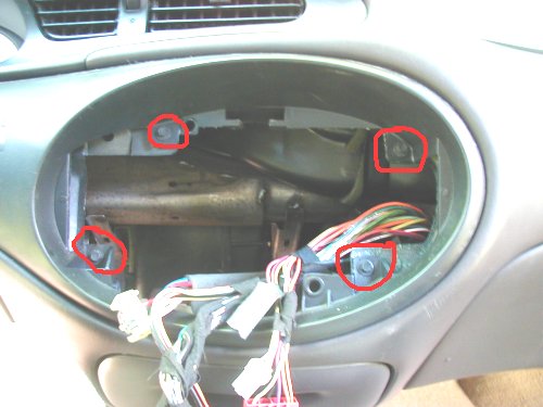 1997 Ford Taurus dashboard interior with exposed wiring and mounting screws circled in red