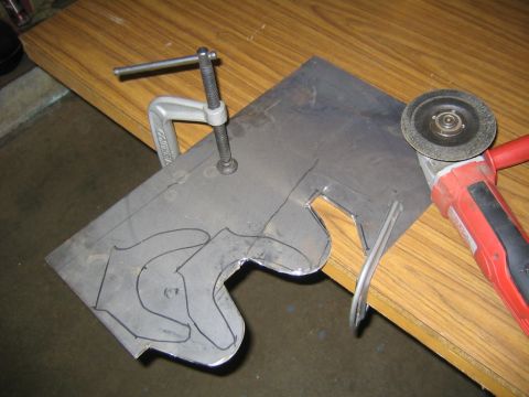 1978 Ford Bronco - A steel plate clamped to a wood-veneer workbench with a metal C-clamp, showing a hand-drawn curved bracket outline in black marker ready to…