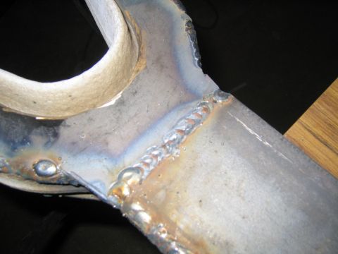 1978 Ford Bronco - Close-up of a TIG-welded steel joint, likely a fabricated suspension arm, showing stacked weld beads with heat-discoloration coloring (blue…