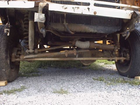 1988 Ford Bronco - Close-up view of the front suspension and grille of a damaged white vehicle.
