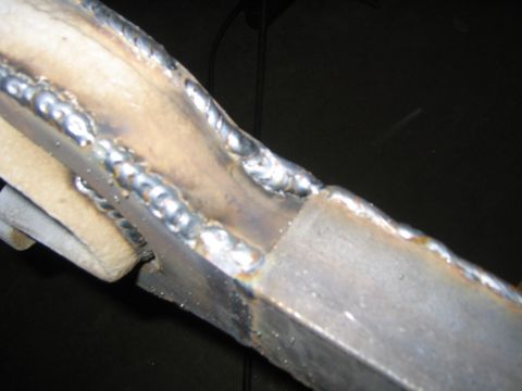 1978 Ford Bronco - Close-up of welded steel tubing joints, showing multiple MIG/TIG weld beads connecting metal members, likely fabricated suspension or roll-…