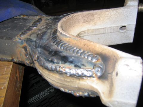 1978 Ford Bronco - Close-up of a cast metal suspension or steering component showing fresh weld beads joining a tubular section to a knuckle-like casting, hel…