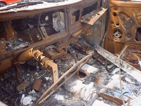 1988 Ford Bronco - The interior of this vehicle is heavily damaged by fire, showing a destroyed dashboard and steering assembly.