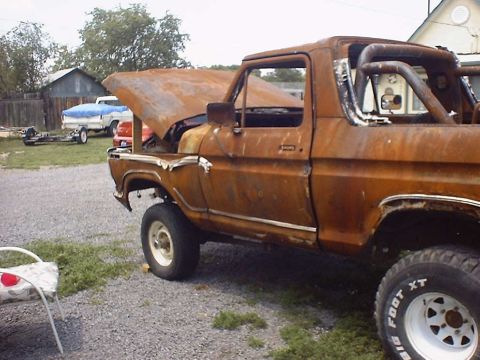 1988 Ford Bronco - This heavily rusted pickup truck is parked outside with its hood open and a roll bar visible in the bed.