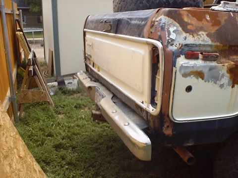 1988 Ford Bronco - Rear view of a heavily rusted 1978 Ford Bronco tailgate with a white insert and chrome bumper.