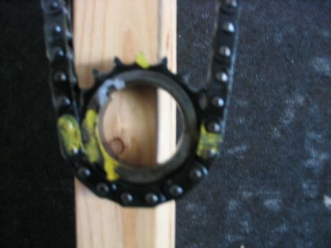 1986 Ford F-150 - A close-up view of a vehicle's timing chain and sprocket, held in place by a wooden block.
