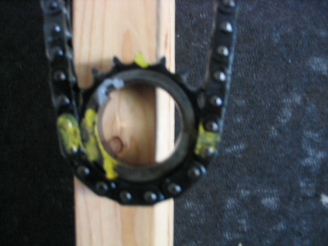 Close-up of a timing chain and sprocket held by a wooden block