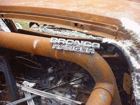 1988 Ford Bronco - The interior of a severely damaged vehicle shows extensive fire and smoke damage, with a 'Bronco Ranger' emblem still attached.