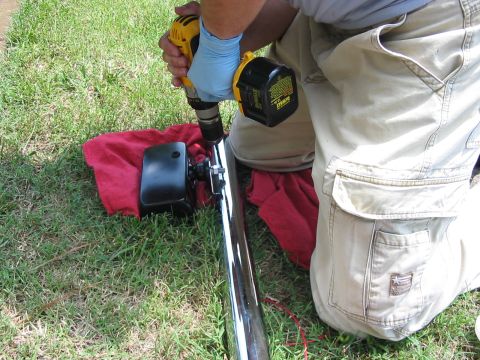 1988 Ford Bronco - Drilling into a chrome pipe with a DeWalt drill, with a red cloth underneath.