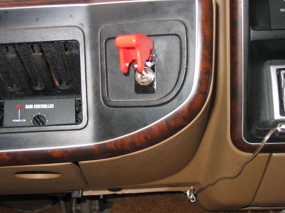 Close-up of a car's dashboard showing a red toggle switch and a gain controller unit