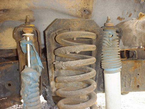 1988 Ford Bronco - Close-up view of heavily rusted suspension parts, including coil springs and shock absorbers.