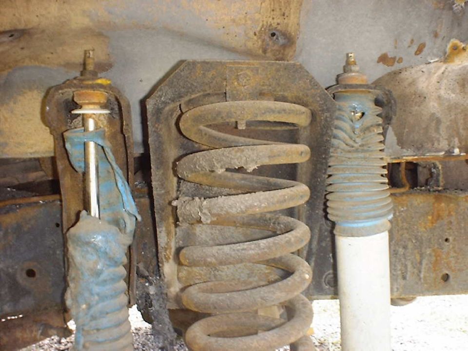Rusty coil springs and shock absorbers, one with a blue cloth wrapped around it