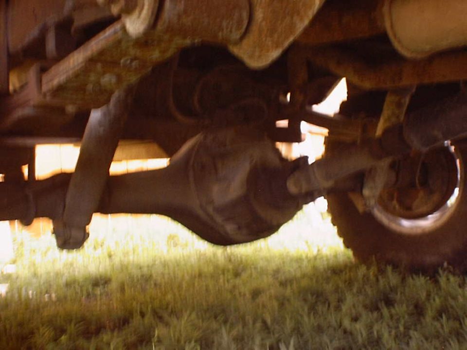 Underside view of a vehicle's rear axle, differential, driveshaft, and suspension parts
