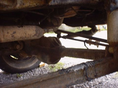 1988 Ford Bronco - The undercarriage of a vehicle reveals its rear axle, suspension, and exhaust system, showing signs of wear and tear.
