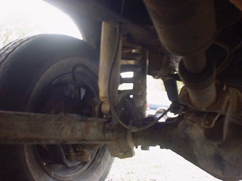 1988 Ford Bronco - Undercarriage view showing the rear suspension components and tire.