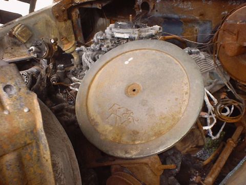 1988 Ford Bronco - The engine compartment of a vehicle shows significant fire damage, with the carburetor and air cleaner assembly visible.