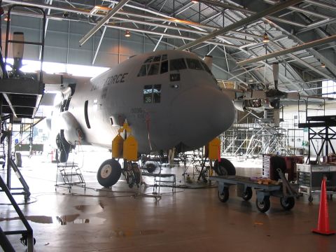 1988 Ford Bronco - A C-130 Hercules aircraft is parked inside a hangar, undergoing maintenance with scaffolding around it.