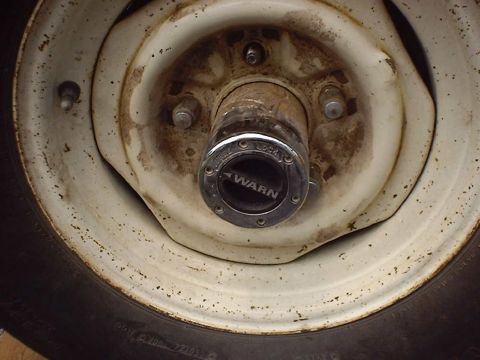 1988 Ford Bronco - Warn locking hub on a white wheel, part of a vehicle's drivetrain.