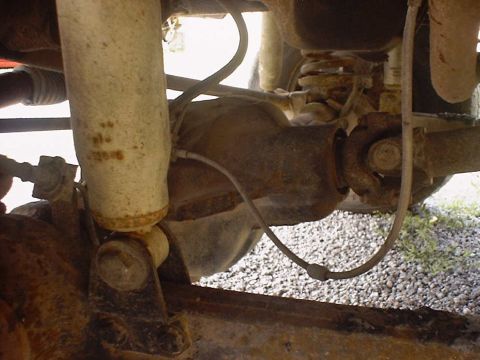 1988 Ford Bronco - Close-up view of the rear axle and suspension components of a vehicle, showing the shock absorber and driveshaft.