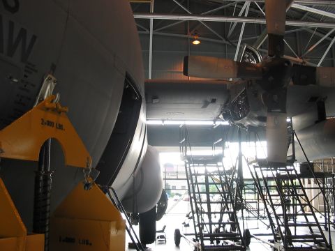 1988 Ford Bronco - A large military transport aircraft is parked inside a hangar, with maintenance equipment nearby.